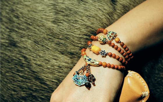 Wrist wearing layered beaded charm bracelets