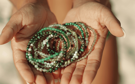 Hands holding green and white beaded bracelets
